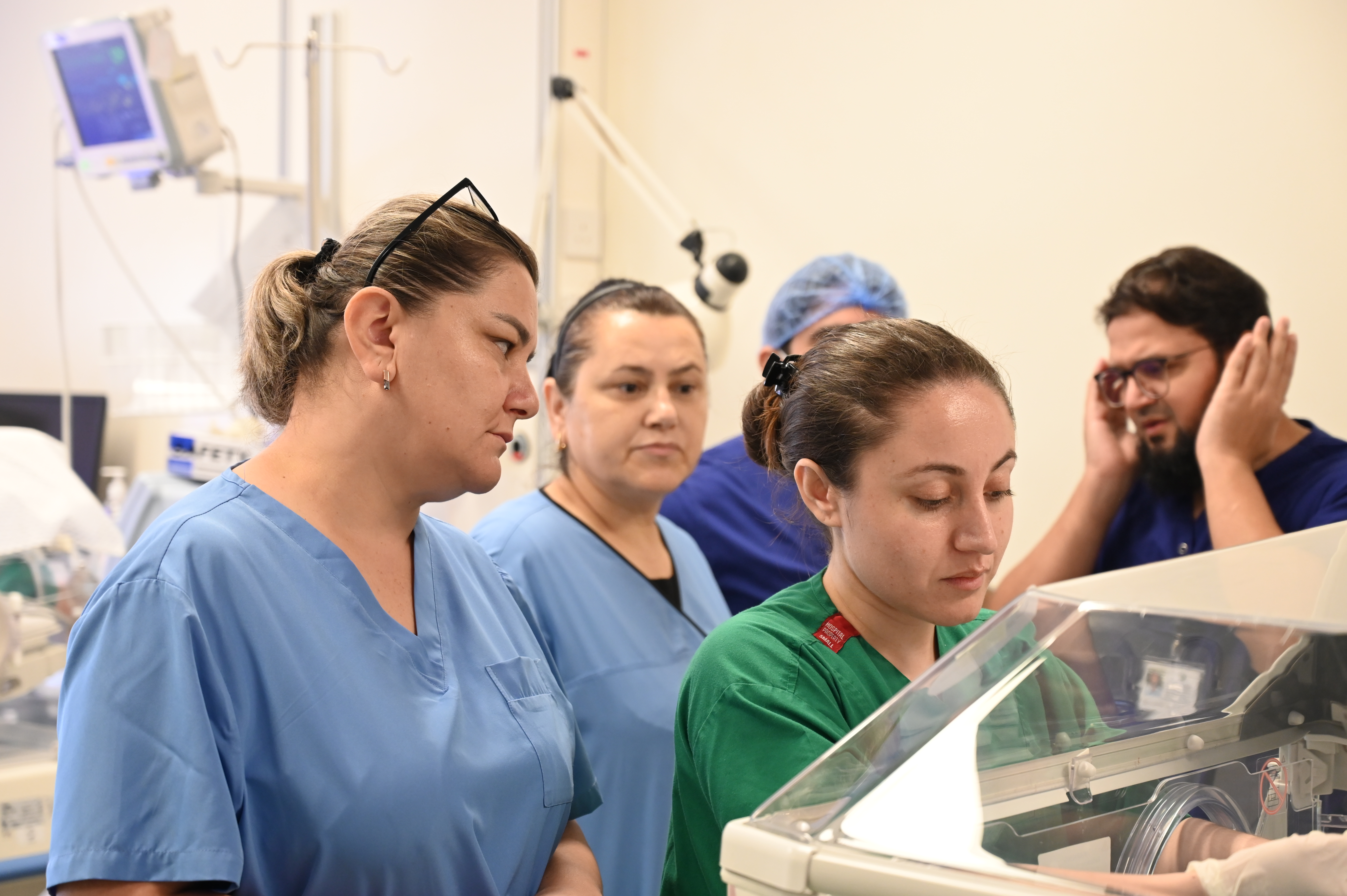 Nurses observe care at an incubator