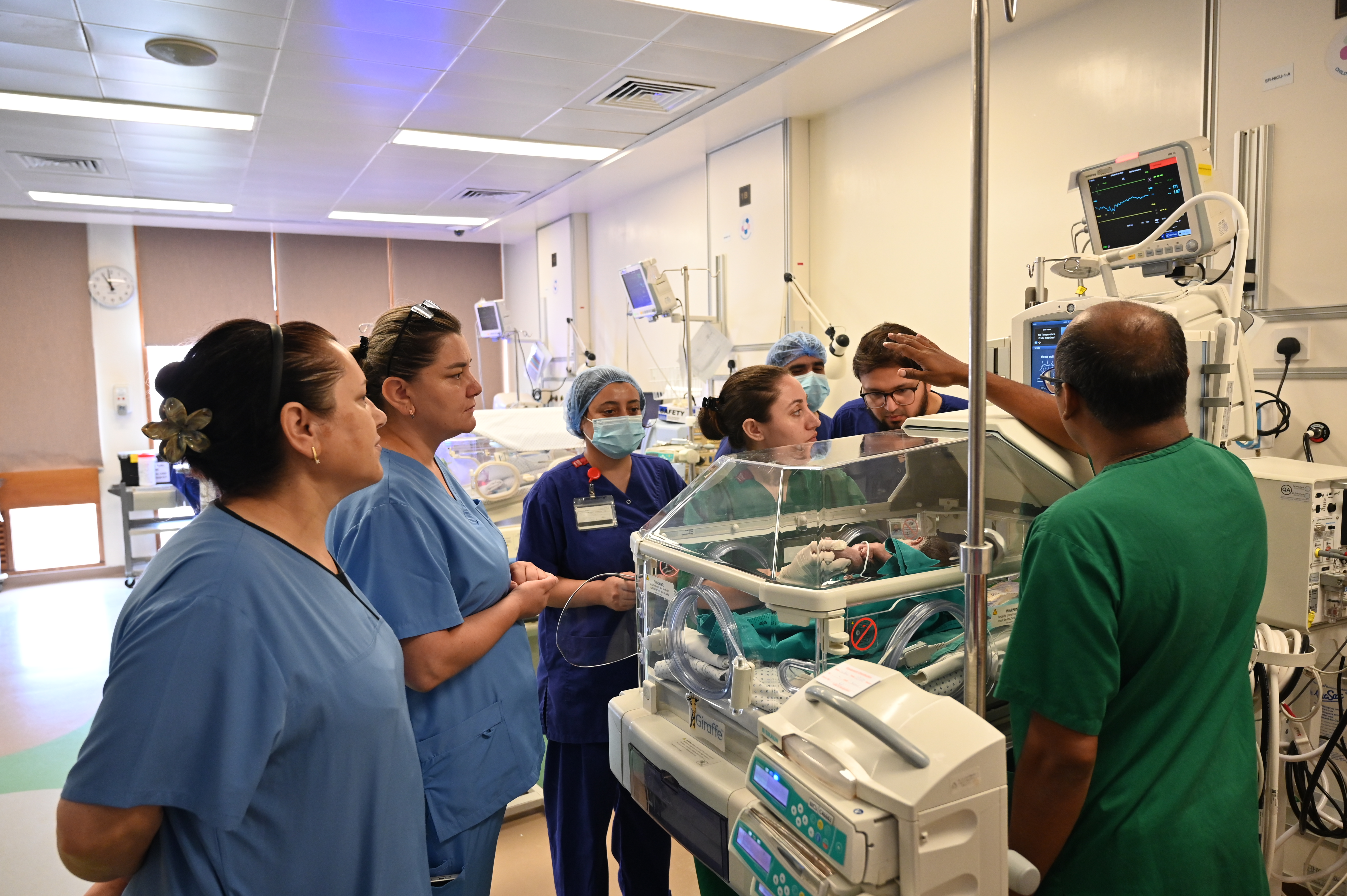 Clinicians and nurses gather around an incubator in the NICU